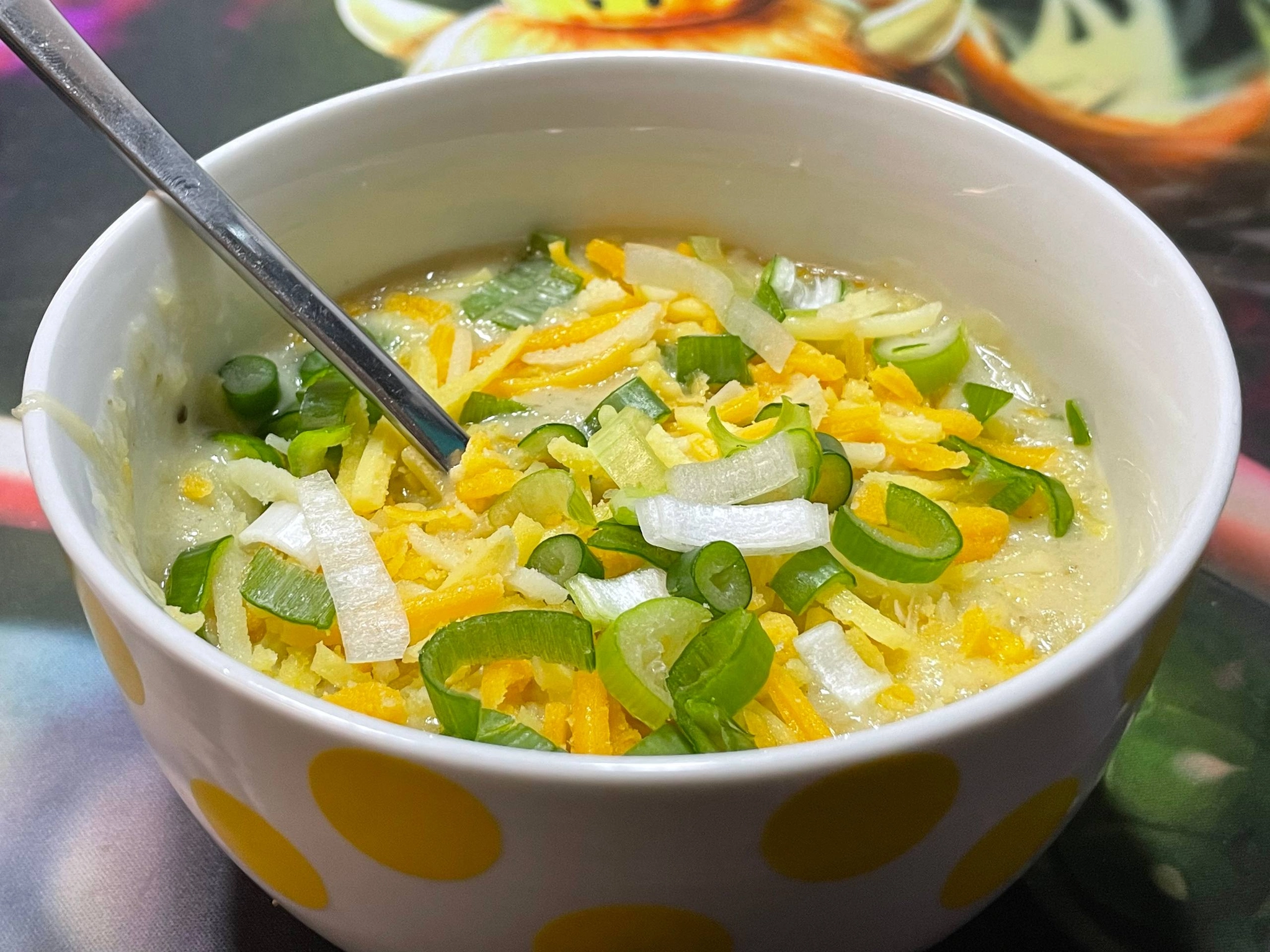 a creamy white soup in a bowl covered in vegan cheese and green onion
